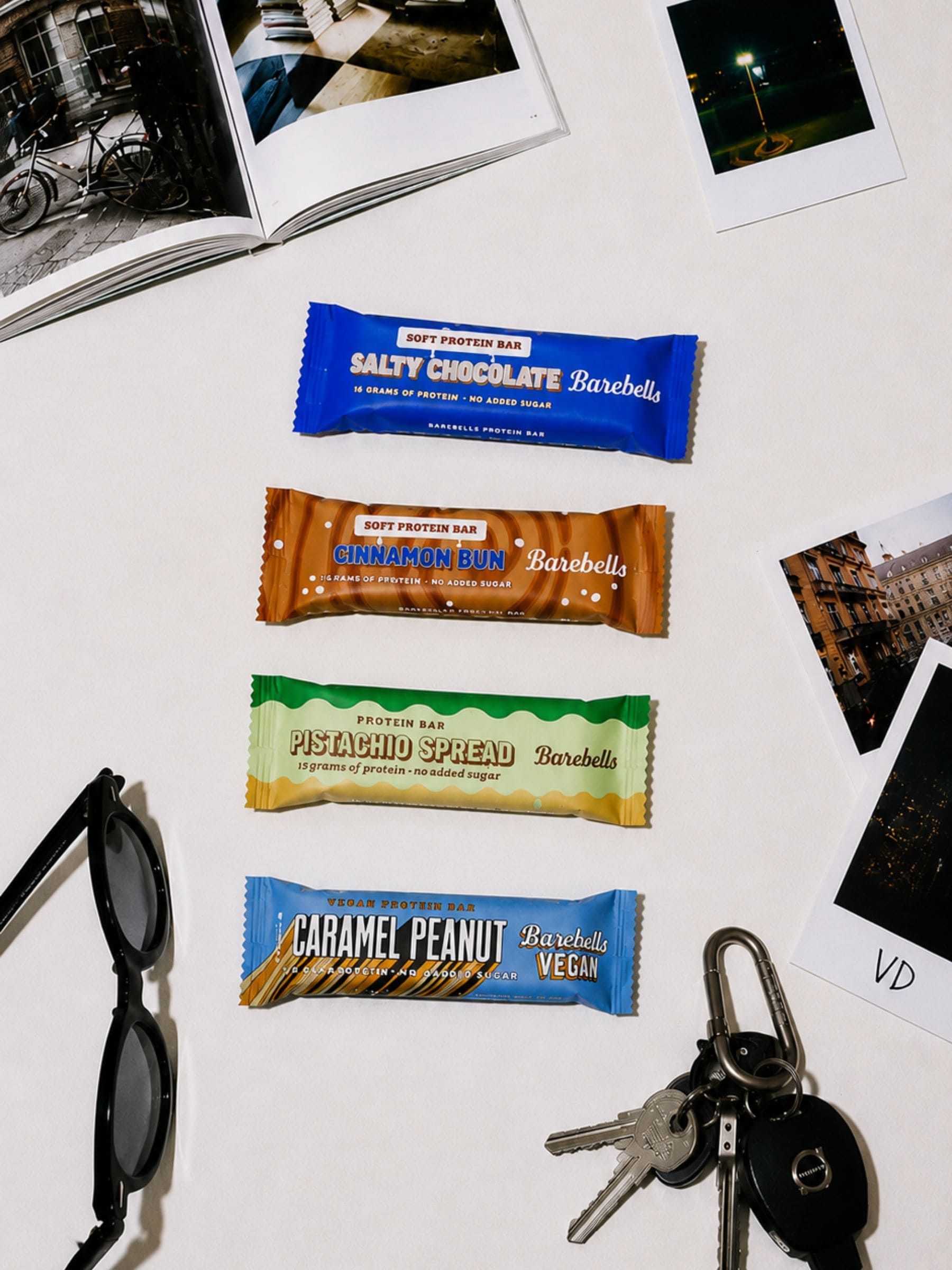 Barebells proteinbars på ett bord med foton och solglasögon