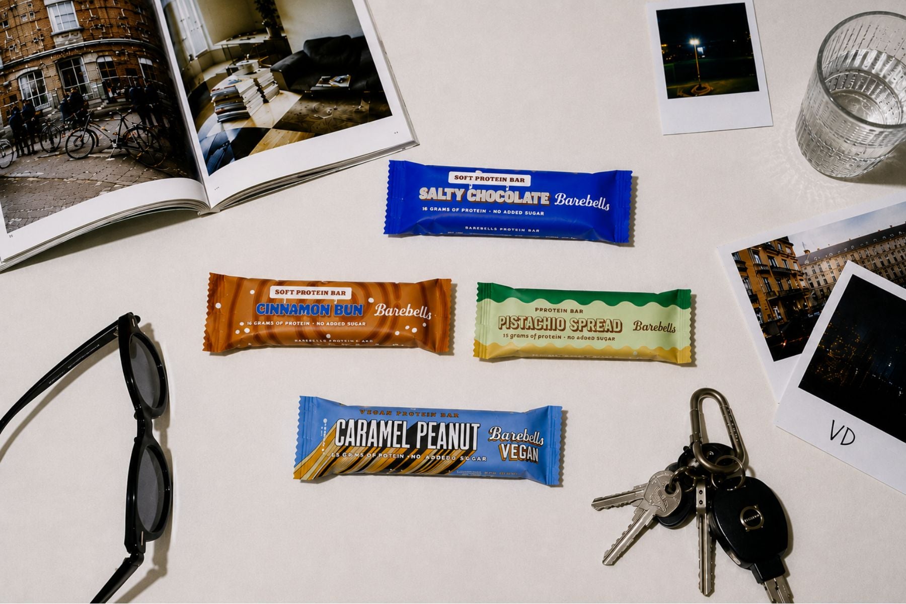 Barebells proteinbars på ett bord med foton och solglasögon